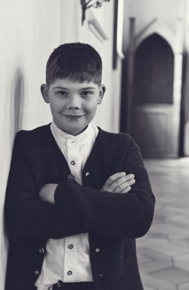 Kommunionkind in festlicher Kleidung bei natürlichem Fotoshooting